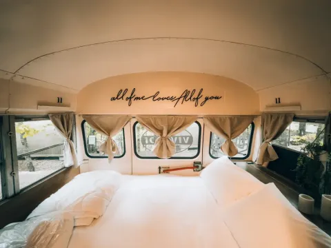 Vue intérieure d’une tiny house dans un bus scolaire avec lit au Chianti Glamping Resort, Italie.