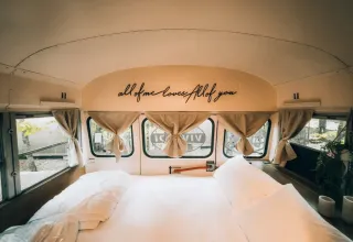 Vue intérieure d’une tiny house dans un bus scolaire avec lit au Chianti Glamping Resort, Italie.