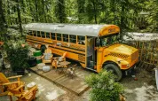 Ein gelber Schulbus wurde als Tiny House mit einer Holzterrasse im Wald beim Chianti Glamping Resort umgebaut.