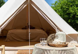 Vue intérieure d'une tente Bell au Thuysgrond aux Pays-Bas, avec un lit et une décoration chaleureuse.
