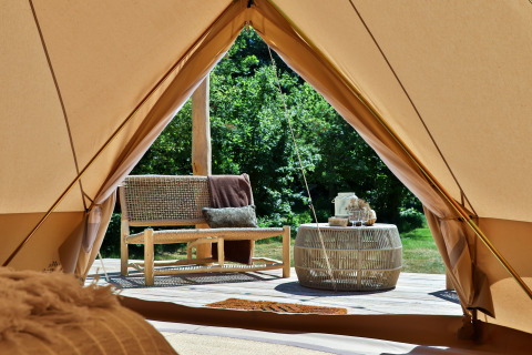 Vista dall'interno di una Bell tent a Thuysgrond, Paesi Bassi, con panca e tavolo sulla terrazza esterna.