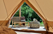 Vista dall'interno di una Bell tent a Thuysgrond, Paesi Bassi, con panca e tavolo sulla terrazza esterna.