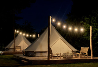 Bell tent tipi’s op Thuysgrond in Nederland, ’s nachts verlicht met lampjes boven houten platforms.