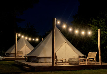 Bell-Zelt als Tipi bei Thuysgrond in den Niederlanden, nachts beleuchtet mit Lichterkette auf Holzdeck.