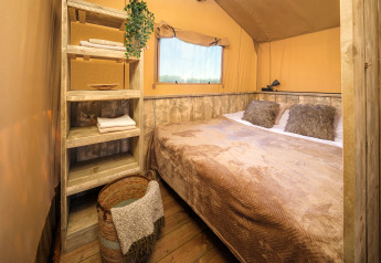 Schlafzimmer im Safari-Zelt Glamp Tent Basic mit rustikalen Holzmöbeln im Weekend Glamping Resort in Italien.
