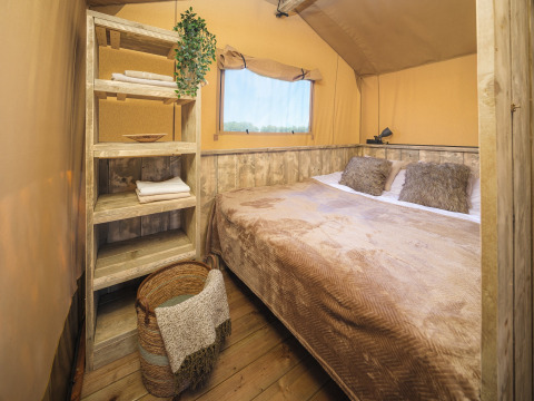 Slaapkamer in de safari tent Glamp Tent Basic met rustieke houten plankjes bij Weekend Glamping Resort in Italië.