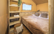 Bedroom inside the Glamp Tent Basic safari tent featuring rustic shelves at Weekend Glamping Resort in Italy.