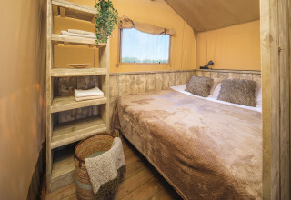Slaapkamer in de safari tent Glamp Tent Basic met rustieke houten plankjes bij Weekend Glamping Resort in Italië.