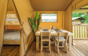 Interiør af Glamp Tent Basic med spisebord og køjeseng på Weekend Glamping Resort i Italien.