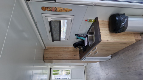 Compact kitchenette with sink, trash bin and window inside a houseboat at Marina Parcs Amsterdam.