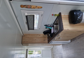 Compact kitchenette with sink, trash bin and window inside a houseboat at Marina Parcs Amsterdam.