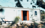 Timber Lodge con terrazza, tende arancioni e sdraio a Eurocamping Vessem BV nei Paesi Bassi.