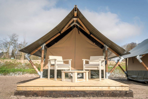 Safaritent Tiny Tent op Camping Waddenzee in Nederland met houten terras en twee stoelen vooraan.