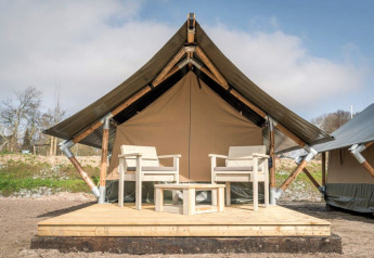 Safaritent Tiny Tent op Camping Waddenzee in Nederland met houten terras en twee stoelen buiten.