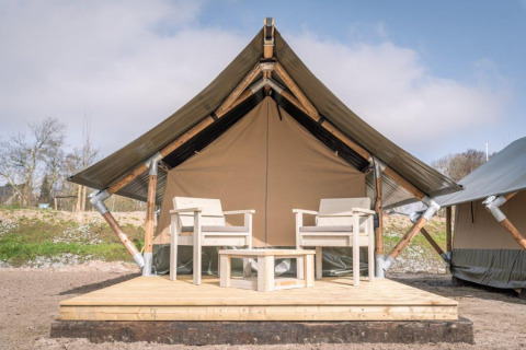 Safari tent Tiny Tent at Campsite Waddenzee in the Netherlands with a wooden deck and two chairs outside.