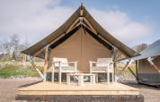 Tienda de safari Tiny Tent en Campsite Waddenzee, Países Bajos, con terraza de madera y dos sillas.