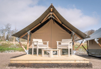 Tienda de safari Tiny Tent en Campsite Waddenzee, Países Bajos, con terraza de madera y dos sillas.