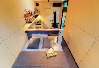 Vue intérieure du Tiny house met spiegelgevel au Holiday park Eigen Wijze avec lit et coin cuisine.