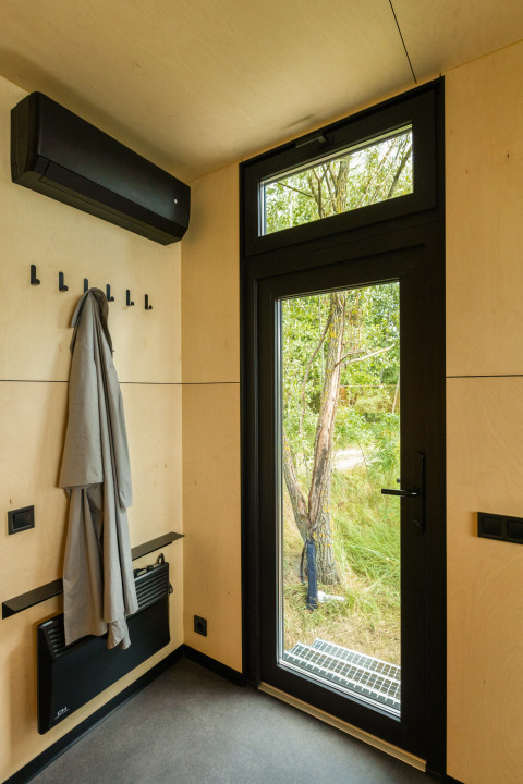 Moderne entré i tiny house med glasdør, sort kant og udsigt til natur, Holiday park Eigen Wijze.