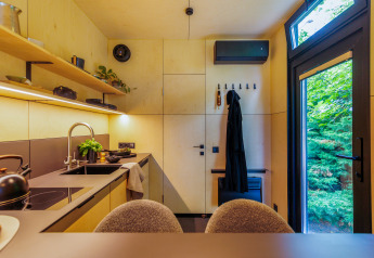 Cuisine moderne et entrée d'une tiny house avec de grandes fenêtres donnant sur un paysage verdoyant.