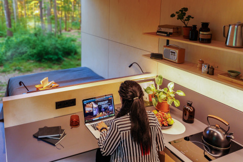 Donna che lavora al computer in una tiny house al Holiday park Eigen Wijze nei Paesi Bassi.