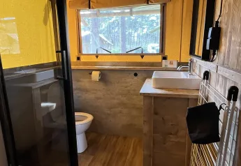 Baño dentro de una tienda safari de lujo en Outdoor Centre Hessenheem, Países Bajos, con comodidades modernas.
