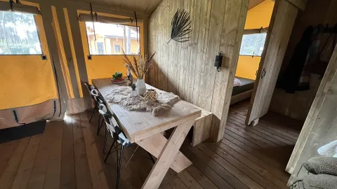 Indvendigt billede af luksus safari telt med spisebord og trævægge på Outdoor Centre Hessenheem, Holland.