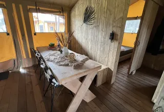 Binnenzicht van luxe safaritent met houten tafel bij Outdoor Centre Hessenheem in Nederland.