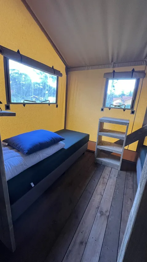 Binnenaanzicht van een luxe safaritent met bed bij Outdoor Centre Hessenheem in Nederland.