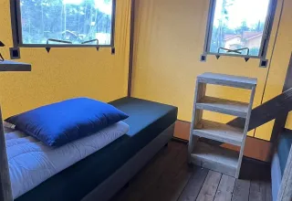 Innenansicht eines luxuriösen Safari-Zelts mit Bett im Outdoor Centre Hessenheem, Niederlande.