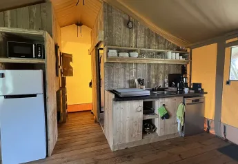 Cocina de tienda safari de lujo en los Países Bajos con nevera, vajilla y lavavajillas.