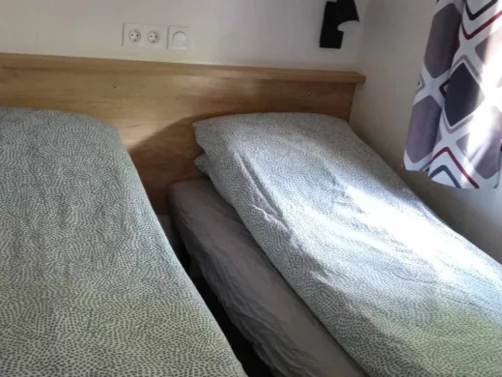 Twee eenpersoonsbedden met grijs beddengoed in een lichte kamer bij Luxe Premium Lodge + jacuzzi, Flower Camping de la Trye.