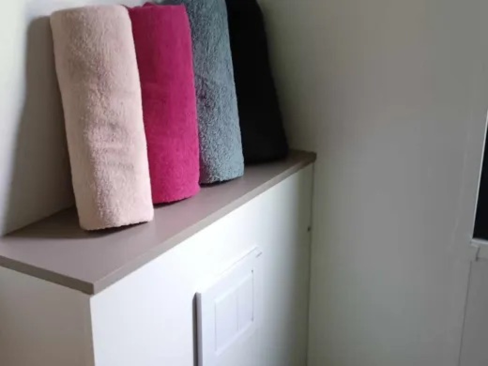 Vier opgerolde handdoeken in verschillende kleuren liggen op een kast in Luxe Premium Lodge in Frankrijk.