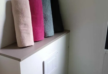 Quatre serviettes roulées de couleurs différentes reposent sur une armoire dans un lodge de luxe français.