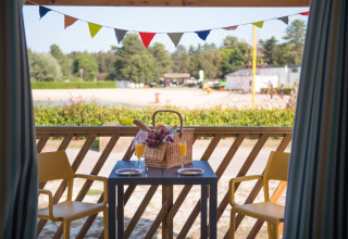 Vista dalle Beach Lodges ad Arden Parks Tulderheyde, Belgio, con tavolo, cestino da picnic e spiaggia sabbiosa.
