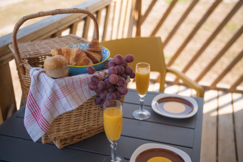 Cestino della colazione con croissant, uva e succo su tavolo ai Beach Lodges, Arden Parks Tulderheyde, Belgio.