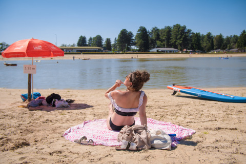 Een vrouw zonnebaadt op het strand van het meer bij Arden Parks Tulderheyde, een vakantiepark in België.