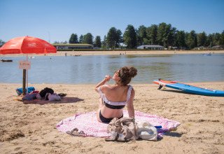 Een vrouw zonnebaadt op het strand van het meer bij Arden Parks Tulderheyde, een vakantiepark in België.