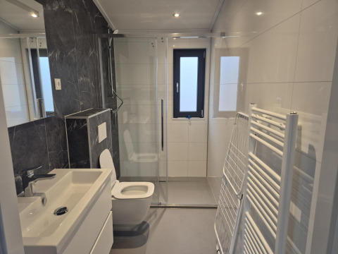Moderne badeværelse i «Cube» Lodge 4, De Utrechtse Heuvelrug, med brusekabine, toilet og vask.