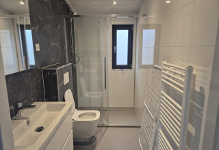 Moderne badeværelse i «Cube» Lodge 4, De Utrechtse Heuvelrug, med brusekabine, toilet og vask.