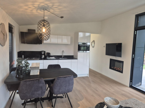 Moderne lodgekøkken og spisestue med sort bord, elegante stole og pejs i De Utrechtse Heuvelrug, Holland.
