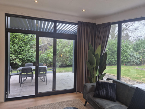 Udsigt fra Cube Lodge 4 på De Utrechtse Heuvelrug i Holland, viser terrasse, have og moderne vinduer.