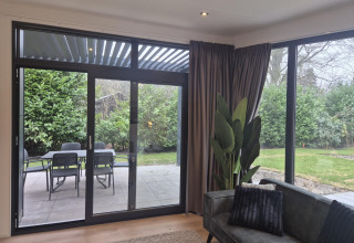 Udsigt fra Cube Lodge 4 på De Utrechtse Heuvelrug i Holland, viser terrasse, have og moderne vinduer.