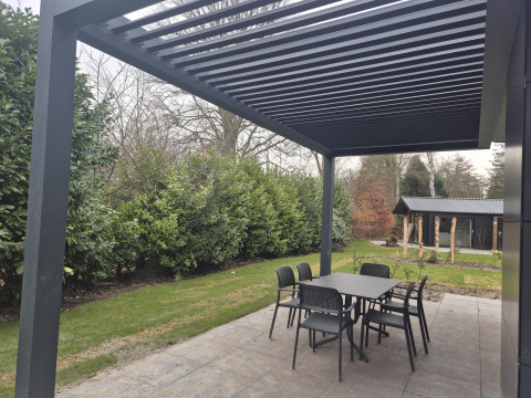 Udendørs spiseområde under en moderne pergola ved Cube Lodge 4 på De Utrechtse Heuvelrug, Nederlandene.