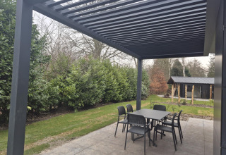 Udendørs spiseområde under en moderne pergola ved Cube Lodge 4 på De Utrechtse Heuvelrug, Nederlandene.