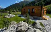 Chalet en bois à Arlberg Cabin au Austriaparks Camping Arlberg, entouré de montagnes et de prairies en Autriche.