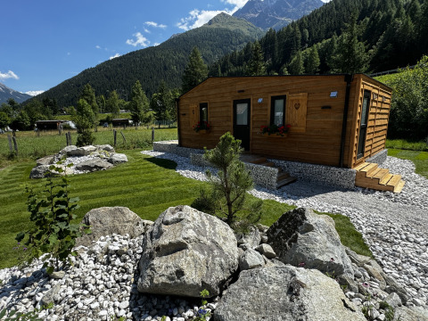 Cabane Arlberg à Austriaparks Camping Arlberg en Autriche, entourée de montagnes, pelouses et rochers.