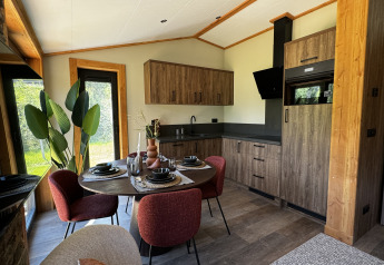 Cocina y comedor modernos en Arlberg Cabin de Austriaparks Camping Arlberg, Austria, con detalles de madera.