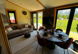 Salon moderne et coin repas avec vue sur les montagnes à Arlberg Cabin, Austriaparks Camping Arlberg, Autriche.