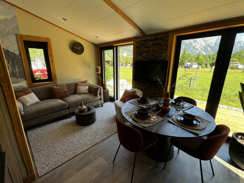 Salon et salle à manger modernes dans la Arlberg Cabin à Austriaparks Camping Arlberg, Autriche, vue sur les montagnes.